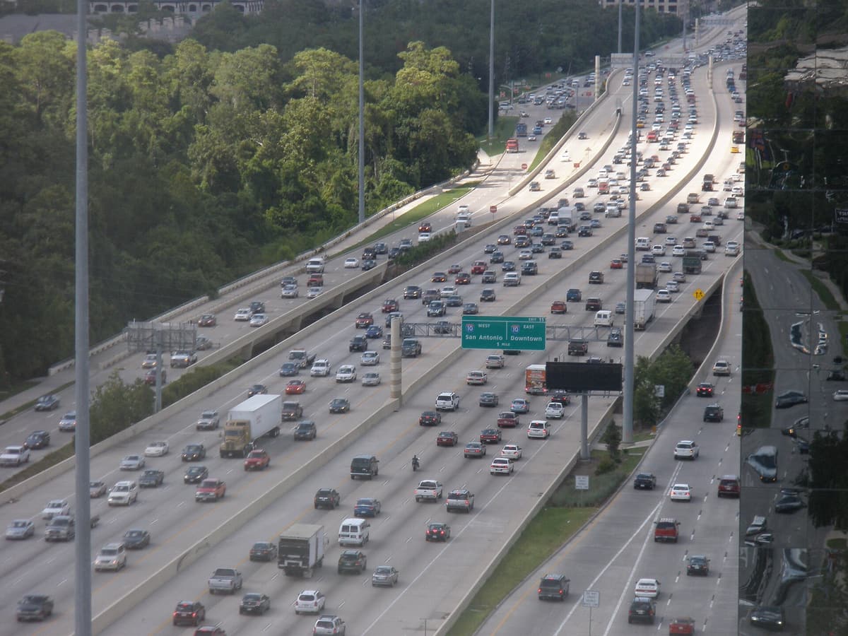 Dense traffic filling all lanes of Interstate 610 West Loop South just south of I-10, seen from a high-rise office building beside the freeway